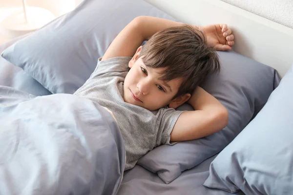 Χαριτωμένο μικρό αγόρι ξαπλωμένη στο κρεβάτι στο σπίτι — Φωτογραφία Αρχείου