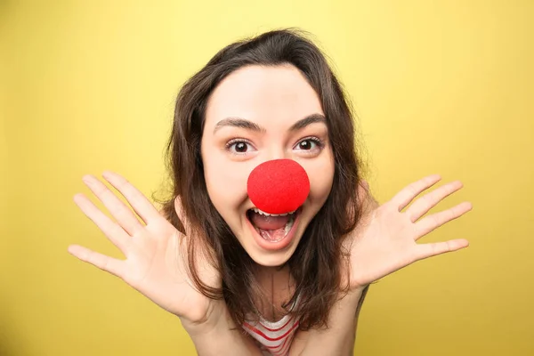 Ung kvinna i roliga förklädnad på färgbakgrund. April fool's day firande — Stockfoto