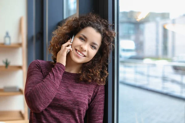 Giovane donna che parla al cellulare al chiuso — Foto Stock