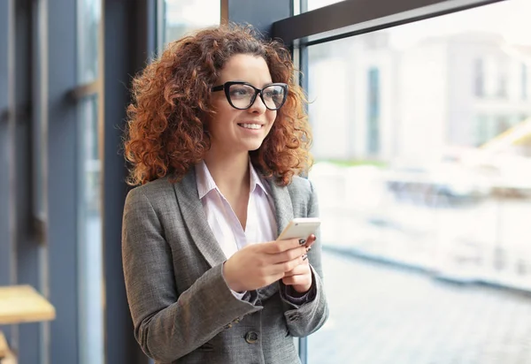 Jeune femme utilisant un téléphone portable à l'intérieur — Photo