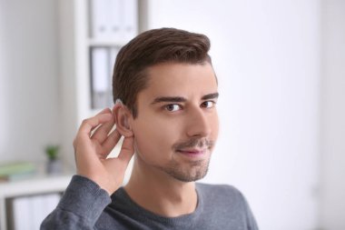 Young man with hearing aid indoors clipart