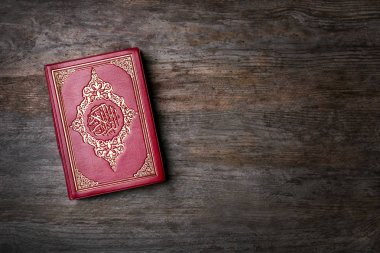 Holy book of Muslims on wooden background clipart