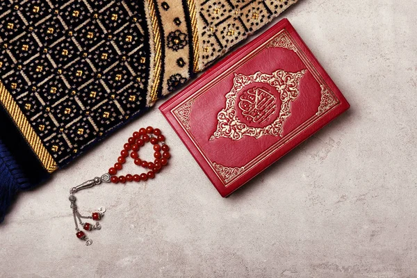 Kitab Suci Muslim, tasbih dan karpet di latar belakang abu-abu — Stok Foto