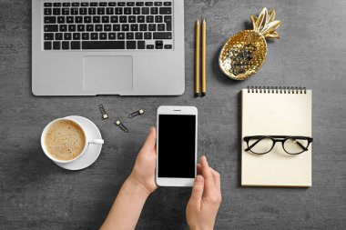 Dizüstü bilgisayar ile masa üzerinde Smartphone tutan kadın