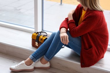 Genç kadın kapalı pencere yanında kırmızı hırka