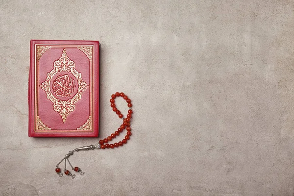 Livro sagrado de muçulmanos e missangas de oração em fundo cinza — Fotografia de Stock