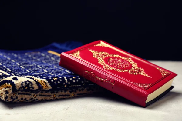 Holy book of Muslims and prayer rug on table — Stock Photo, Image