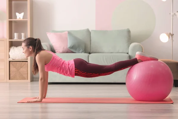 Belle jeune femme faisant des exercices de fitness avec balle à la maison — Photo