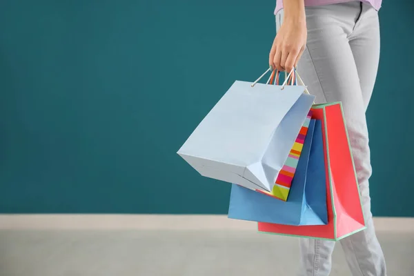 Mujer joven con bolsas de compras contra la pared de color —  Fotos de Stock