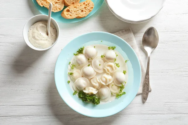 Smakrik buljong med dumplings på träbord — Stockfoto