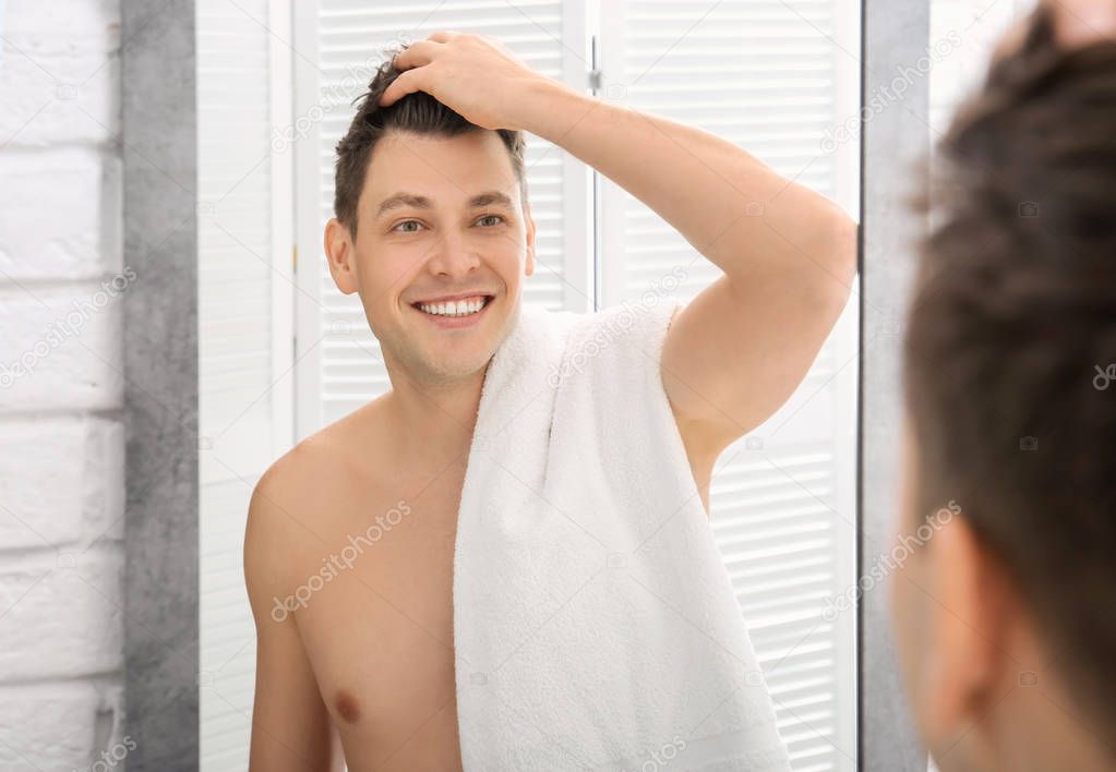 Handsome shaved man near mirror in bathroom