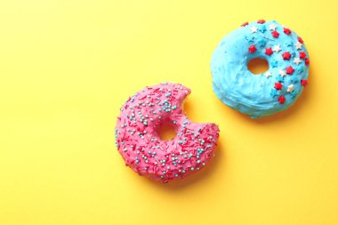 Delicious colorful donuts on color background clipart