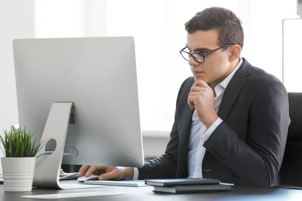 Молодой человек в офисной одежде работает за столом с компьютером — стоковое фото