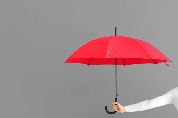 Mujer sosteniendo elegante paraguas rojo sobre fondo gris — Foto de Stock