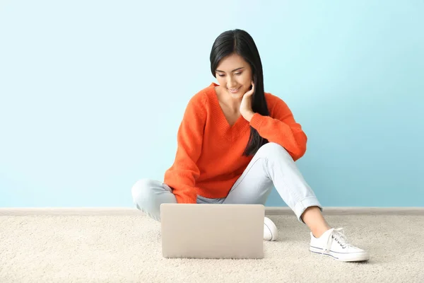 Jeune femme asiatique en utilisant un ordinateur portable sur le sol à l'intérieur — Photo