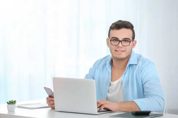 Jeune homme travaillant avec un ordinateur portable à la table dans le bureau à domicile — Photo