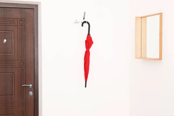 Elegante paraguas rojo colgando cerca de la puerta y espejo en la pared —  Fotos de Stock