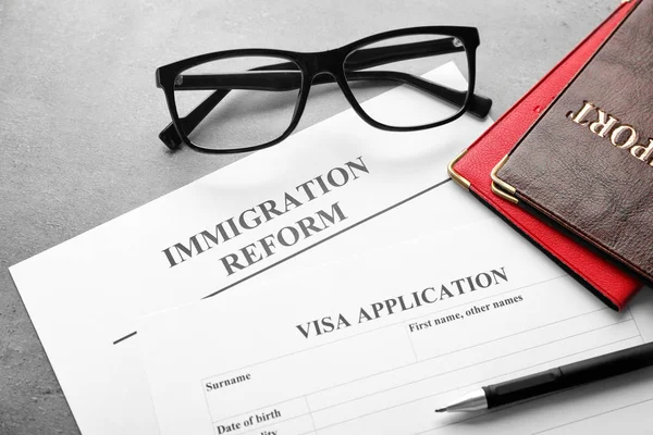 Passaportes, óculos e formulário de pedido de visto na mesa. Reforma da imigração — Fotografia de Stock