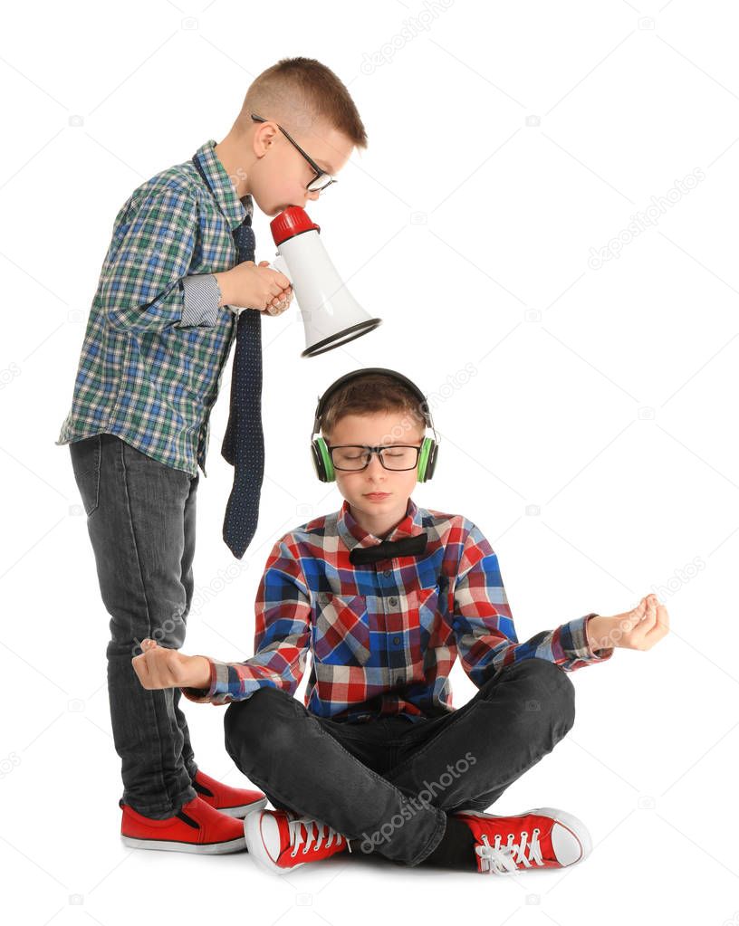 Cute little boy meditating and ignoring his friend with megaphone, on white background