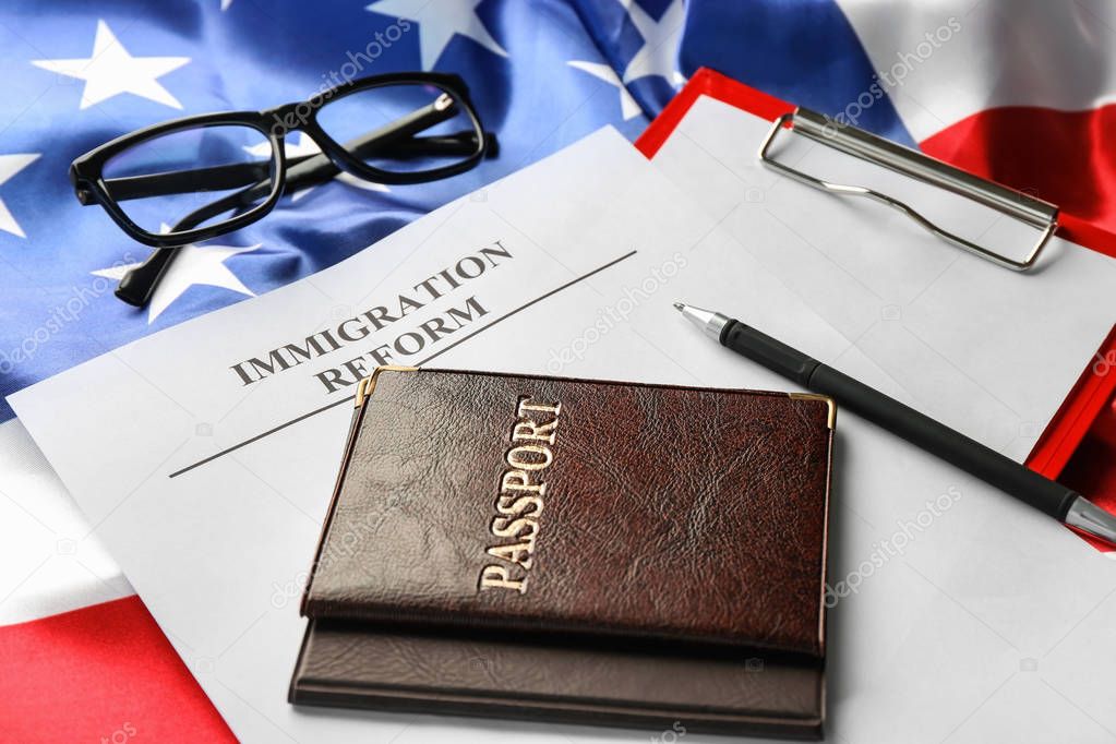 Passports and sheet of paper with words IMMIGRATION REFORM on American flag