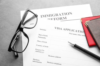 Passports, glasses and visa application form on table. Immigration reform clipart