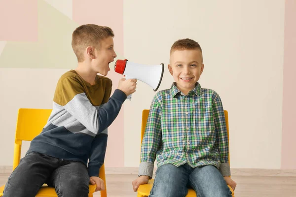 Смішний маленький хлопчик кричить на свого друга, використовуючи мегафон — стокове фото