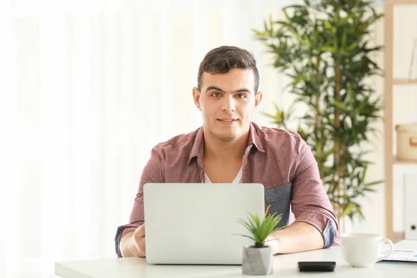 Hombre joven que trabaja con el ordenador portátil en la oficina en casa — Foto de Stock