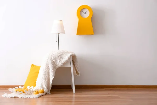 Елегантна лампа і ковдра на столі в інтер'єрі кімнати біля світлої стіни — стокове фото