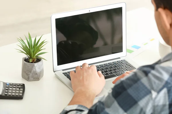 Ung man arbetar med laptop vid bordet, närbild — Stockfoto