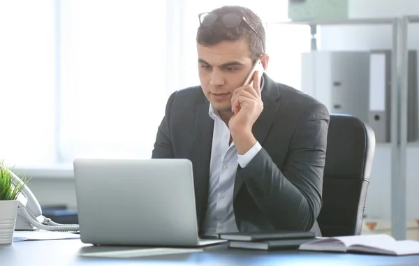 Joven en ropa de oficina hablando por teléfono en el lugar de trabajo — Foto de Stock