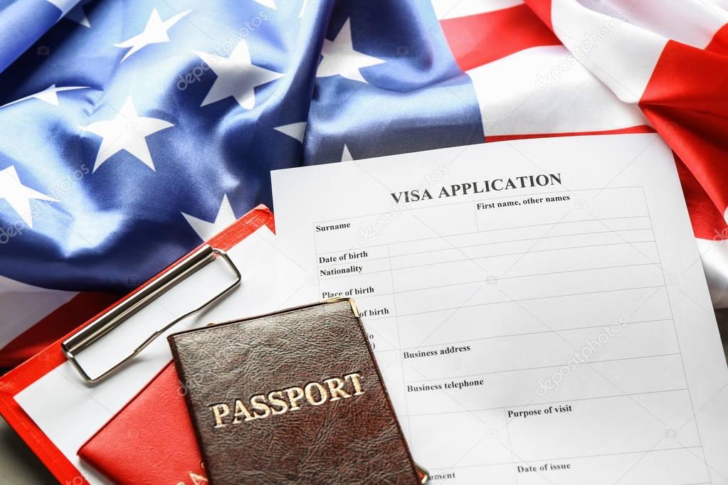 Passports, American flag and visa application form on table. Immigration to USA