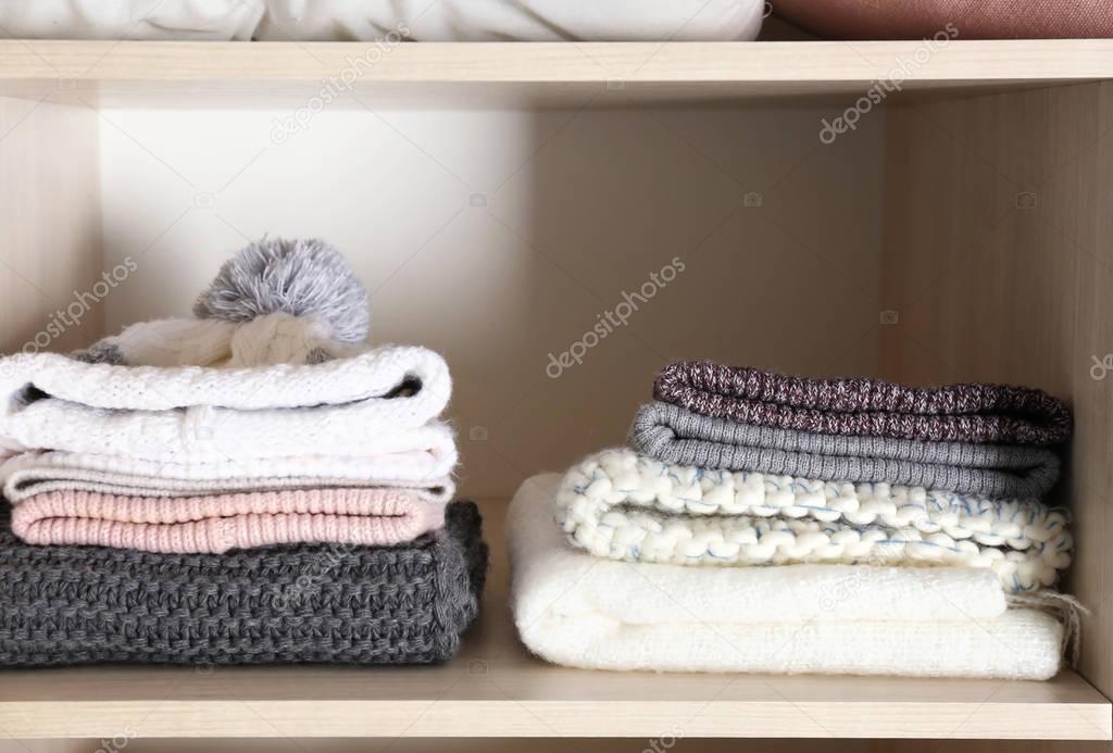 Warm hats and scarves on shelf of wardrobe closet