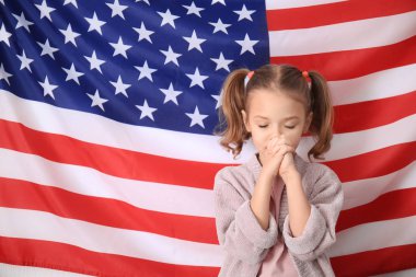 Amerika ve bayrak için dua sevimli küçük kız arka plan üzerinde