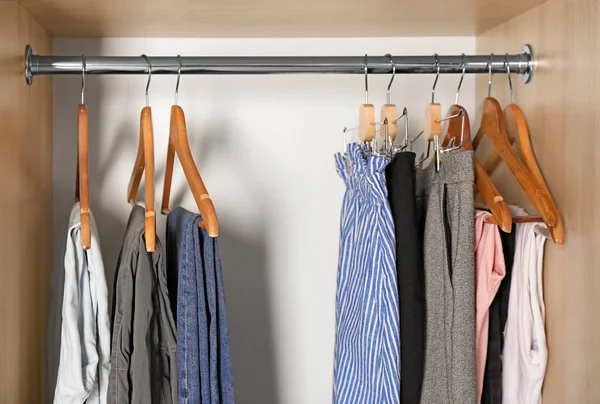 Hangers met verschillende kleren in garderobe kast — Stockfoto