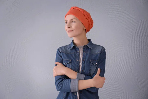 Jonge vrouw met kanker in hoofddoek op grijze achtergrond — Stockfoto