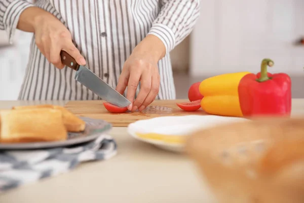 Frau schneidet Tomaten für leckeren Toast an Bord am Tisch — Stockfoto