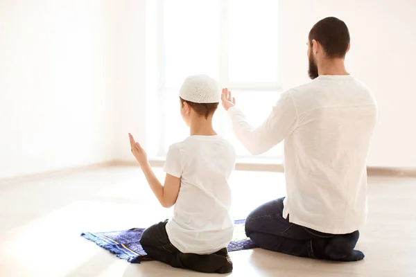 Pai e filho muçulmanos rezando juntos, dentro de casa — Fotografia de Stock
