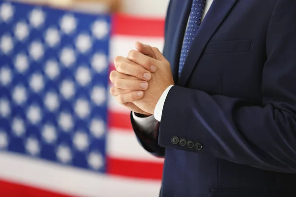 Jovem de terno rezando pela América e bandeira em segundo plano — Fotografia de Stock