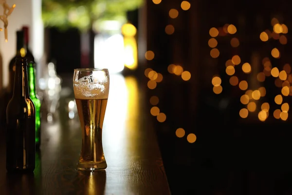 Bicchiere di birra sul tavolo contro sfondo sfocato — Foto Stock