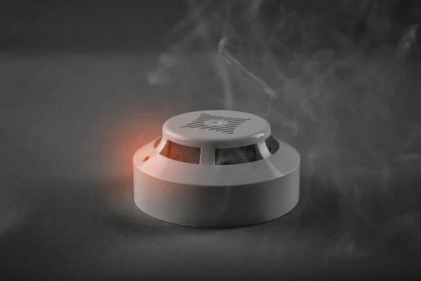 Detector de humo con luz de advertencia sobre fondo gris —  Fotos de Stock