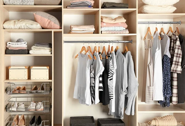 Large wardrobe closet with different clothes and shoes