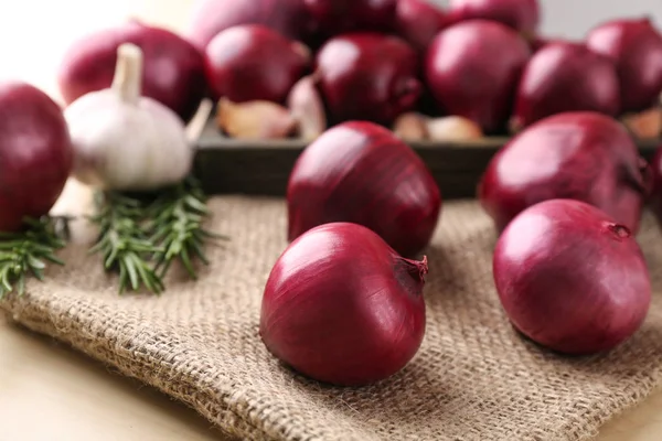 Cebollas rojas maduras, ajo y romero en la mesa —  Fotos de Stock