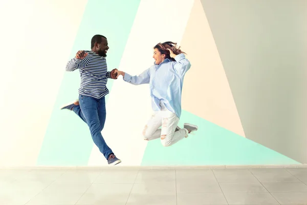 Linda pareja interracial saltando contra la pared de color — Foto de Stock