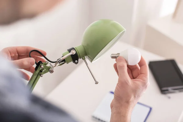 Mann wechselt Glühbirne in Lampe zu Hause — Stockfoto