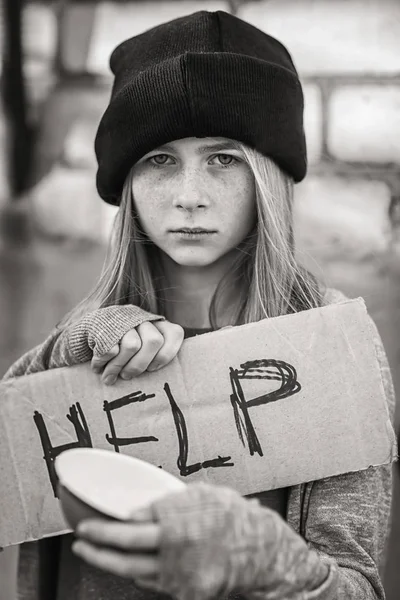 Dakloze arme tienermeisje holding leeg kom en stuk karton met word Help buitenshuis — Stockfoto