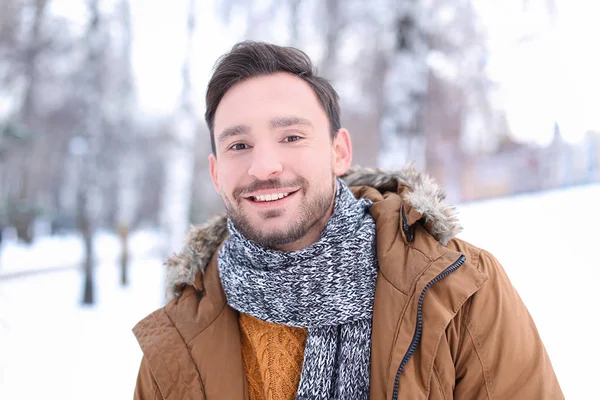 Schöner Mann im verschneiten Park im Winterurlaub — Stockfoto