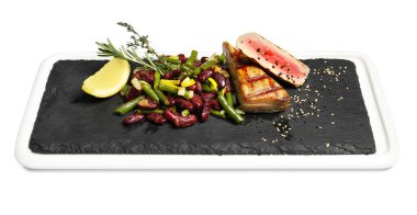 Lezzetli ızgara orkinos ve beyaz arka plan üzerinde fasulye ile kayrak plaka