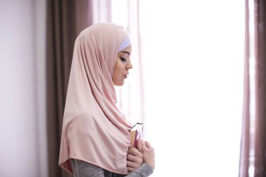 Kur'an tutarak ve dua, kapalı genç Müslüman kadın
