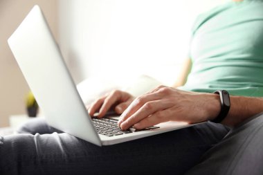 Genç adam evde dizüstü bilgisayar kullanıyor.