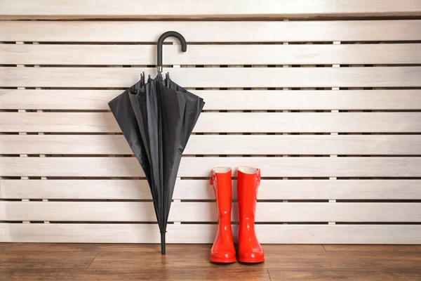 Black umbrella and gumboots on floor indoors — Stock Photo, Image